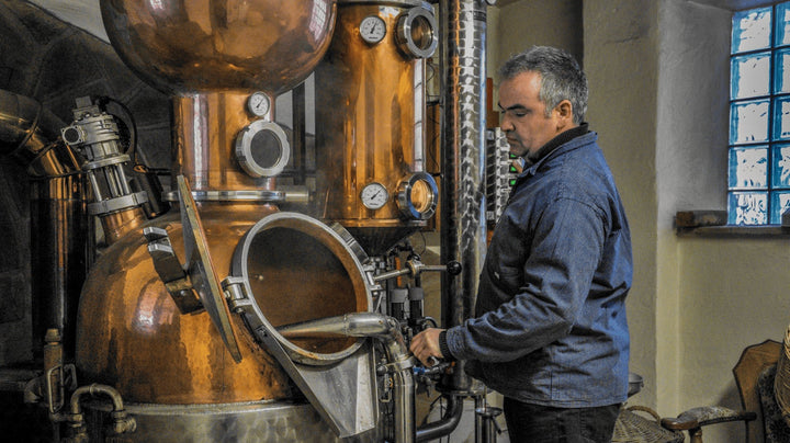Der Brenner Klemens Kammerer steht an seinem Brennkessel und destilliert Schnaps.
